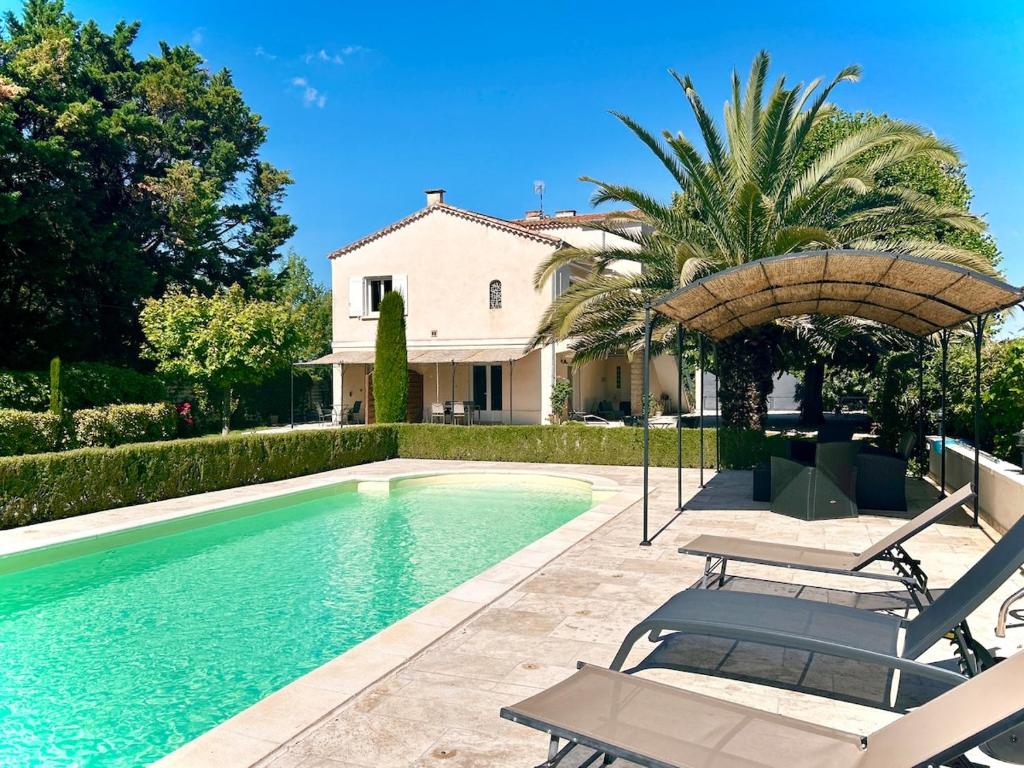 ein Haus mit einem Pool mit Stühlen und einem Sonnenschirm in der Unterkunft Villa 7 chambres, piscine et jardins privés, pas de voisins in Le Thor
