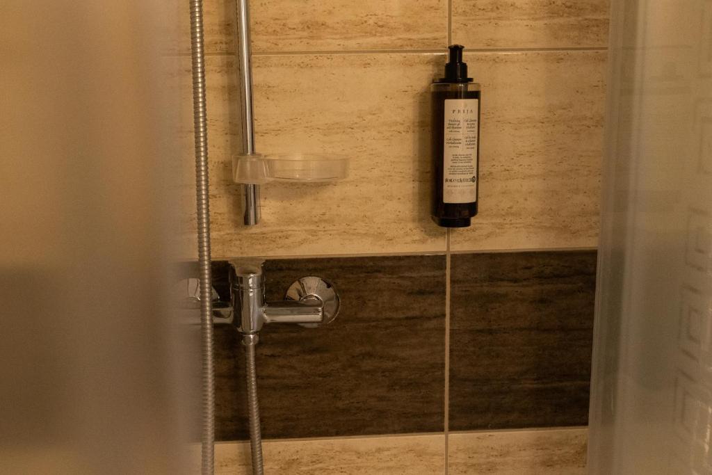 Shower area with beige tiles and mounted shampoo bottle.