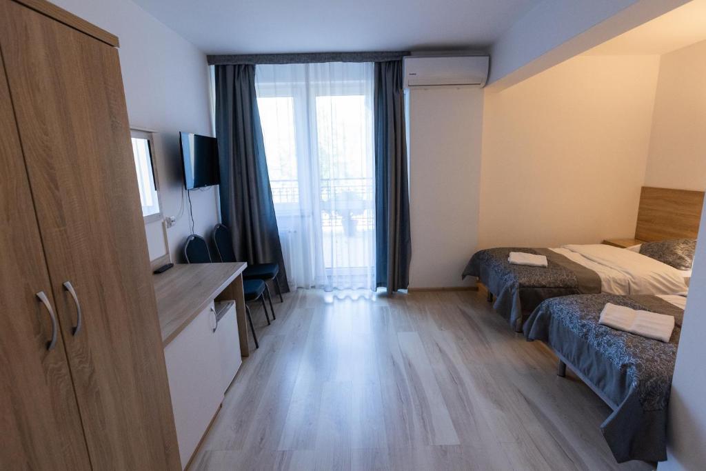 Spacious room with desk, TV, and twin beds near a window.