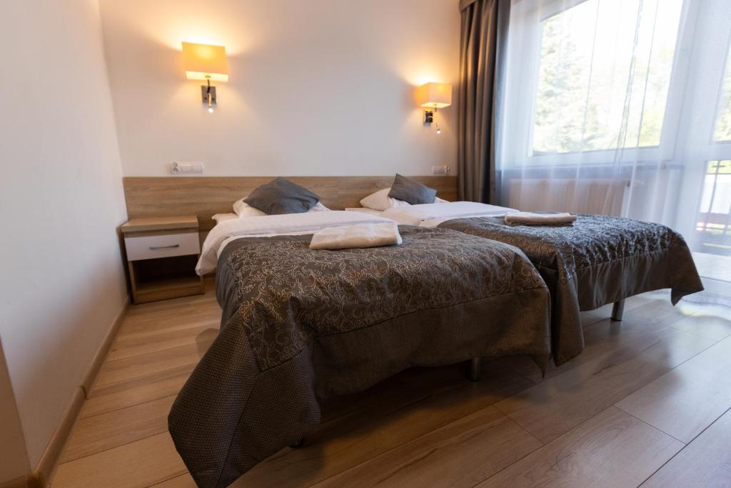 Room with twin beds, bedside lamps, and large window with view.