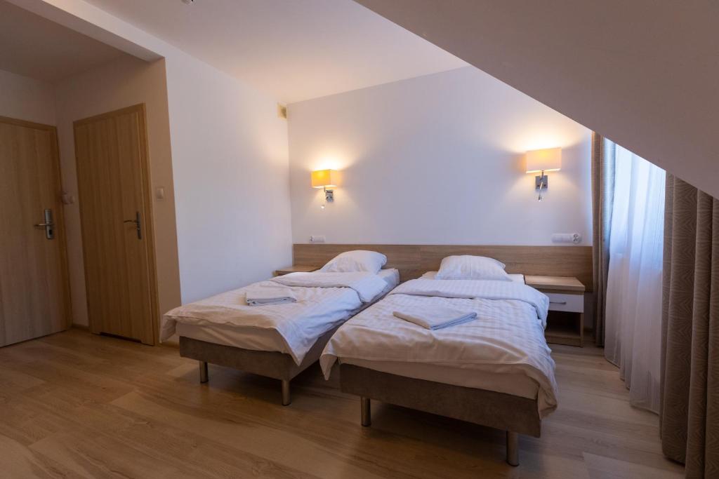 Room with two single beds, wooden flooring, and bedside lamps.