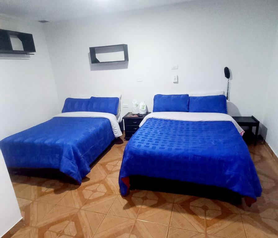 two beds in a room with blue sheets at Hotel Parkway Inn 58 Street in Bogotá