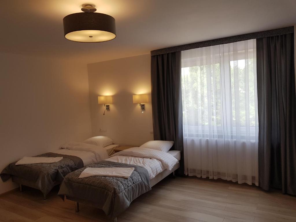 Room with two beds, large window, and modern ceiling light.