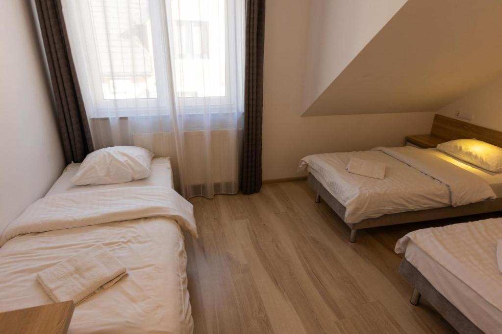 Simple room with three beds, wooden flooring, and a large window.