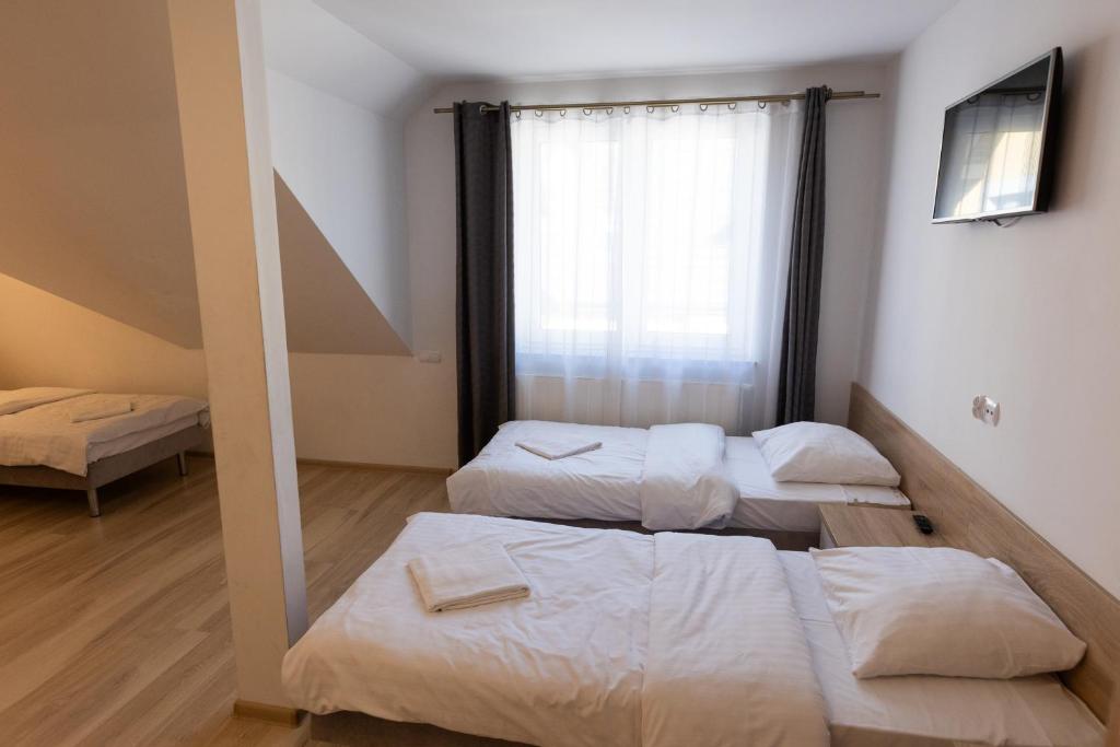 Room with two single beds, TV, and large window with curtains.