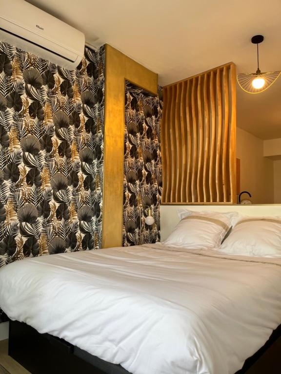 - une chambre avec un grand lit blanc et un mur dans l'établissement InstantNu, au Cap d'Agde