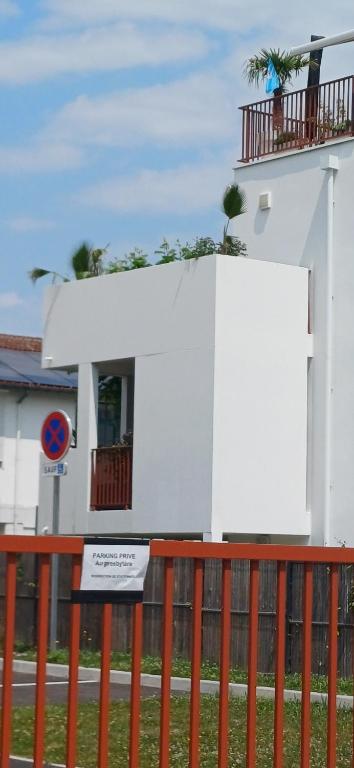 un bâtiment blanc avec un panneau sur une clôture dans l'établissement Appartement avec terrasse, proche centre, à Bayonne