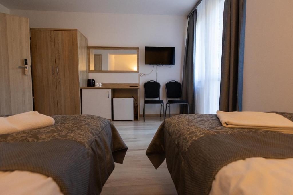 Cozy room with two beds, wooden furniture, and a wall-mounted TV.