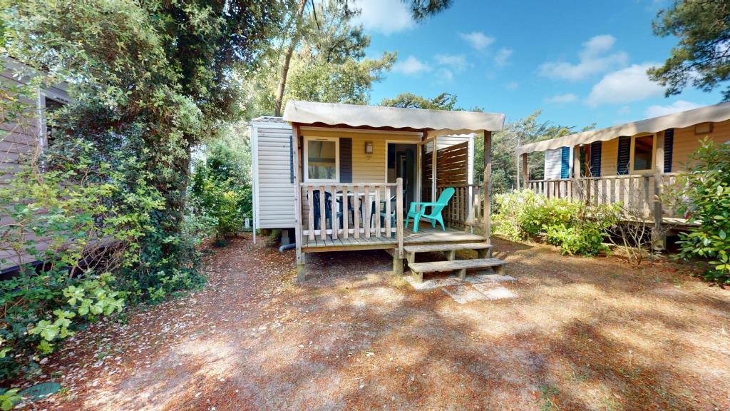 une petite maison avec un porche et une chaise verte dans l'établissement Cabane des Dunes, à Saint-Jean-de-Monts