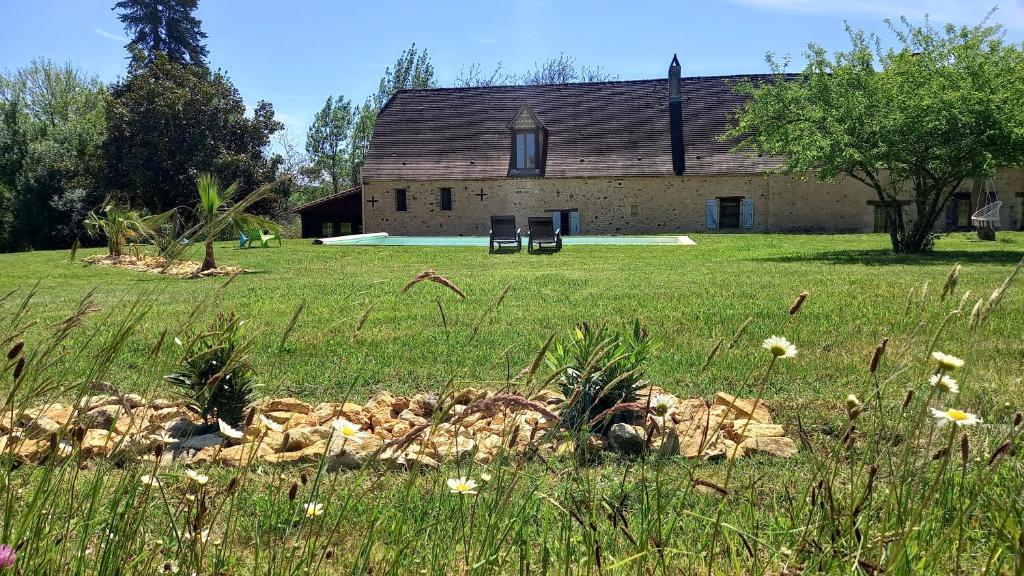 un ancien bâtiment dans un champ avec un mur en pierre dans l'établissement L'Ecrin du Val de Louyre, à Lentignac