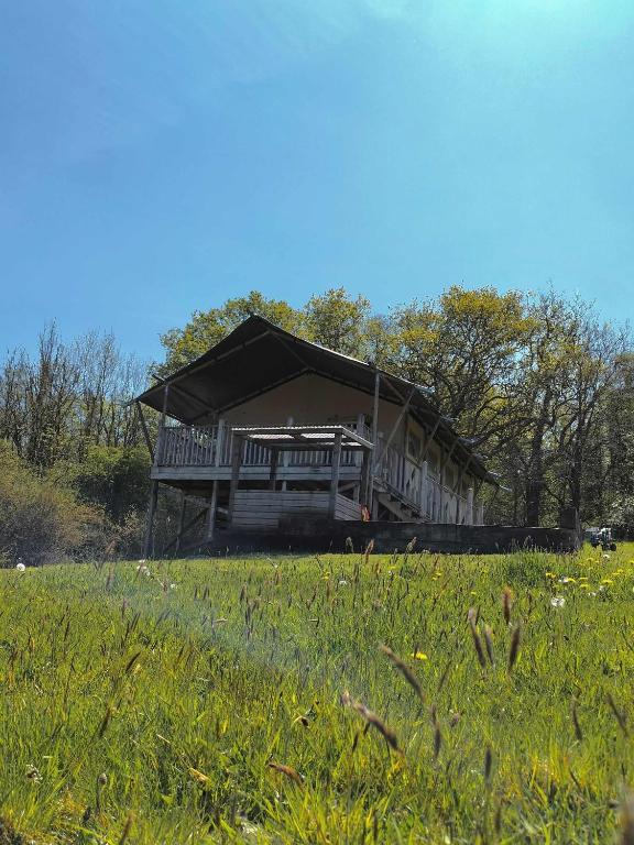 a large house with a porch in a field at Beara Lodge Glamping in Beaworthy