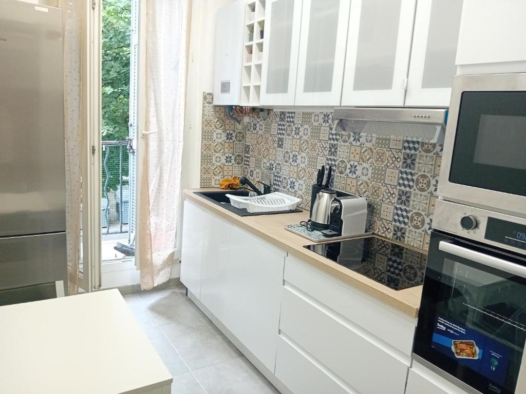 une cuisine avec des armoires blanches et un micro-ondes dans l'établissement Baya en vacances, à Marseille