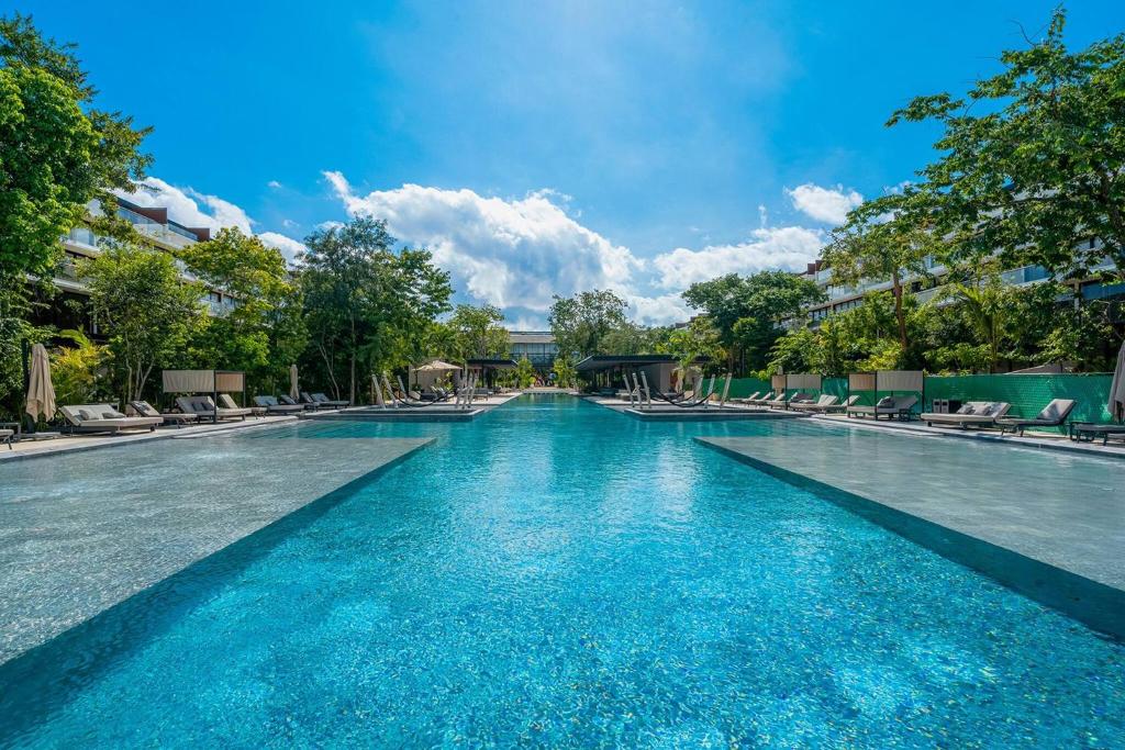 einen Pool mit blauem Wasser und Liegestühlen in der Unterkunft Luxury 3 Bedroom Condo - Infinity Pool - AWA Residences - Condo Anahuac 110 in Playa del Carmen