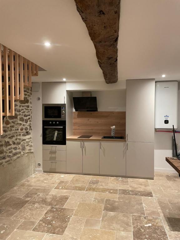 - une cuisine avec des placards blancs et un mur en pierre dans l'établissement Maison fraîchement rénovée, à Saint-Pierre-de-Plesguen