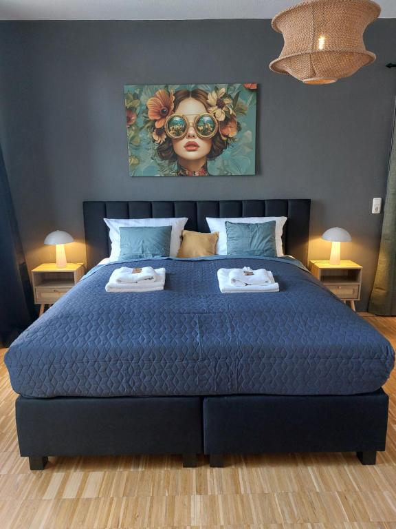 a bedroom with a blue bed with a painting of a woman at maremar - Luxus Boxspringbett - Küche - Arbeitsplatz - WLAN in Verden