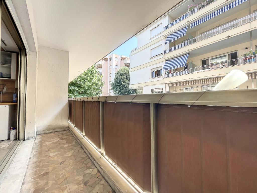 - un balcon avec une clôture en bois et un bâtiment dans l'établissement Un Coin de Plage, à Antibes