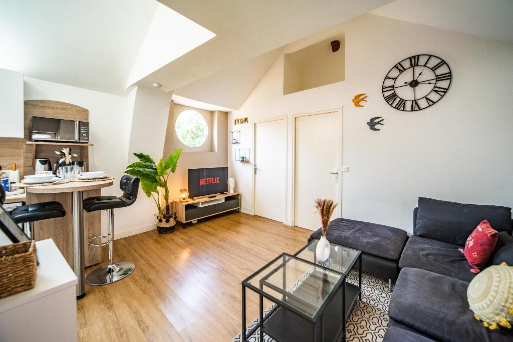 a living room with a couch and a clock on the wall at Le Ballanais - Parking - Netflix in Ballan-Miré