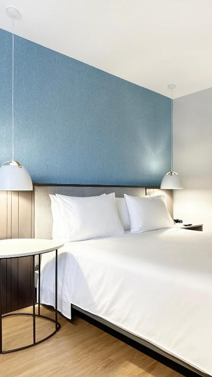 a bedroom with a large white bed and two pendant lights at Hotel Habitel Select in Bogotá
