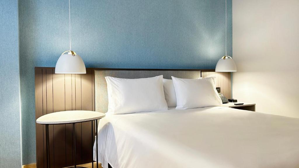 a bedroom with a large white bed with two lights at Hotel Habitel Select in Bogotá