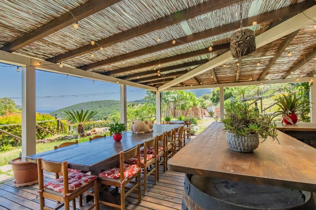 an outdoor dining area with a wooden table and chairs at Tra Cielo e Mare Rooms Rio Marina in Rio nellʼElba