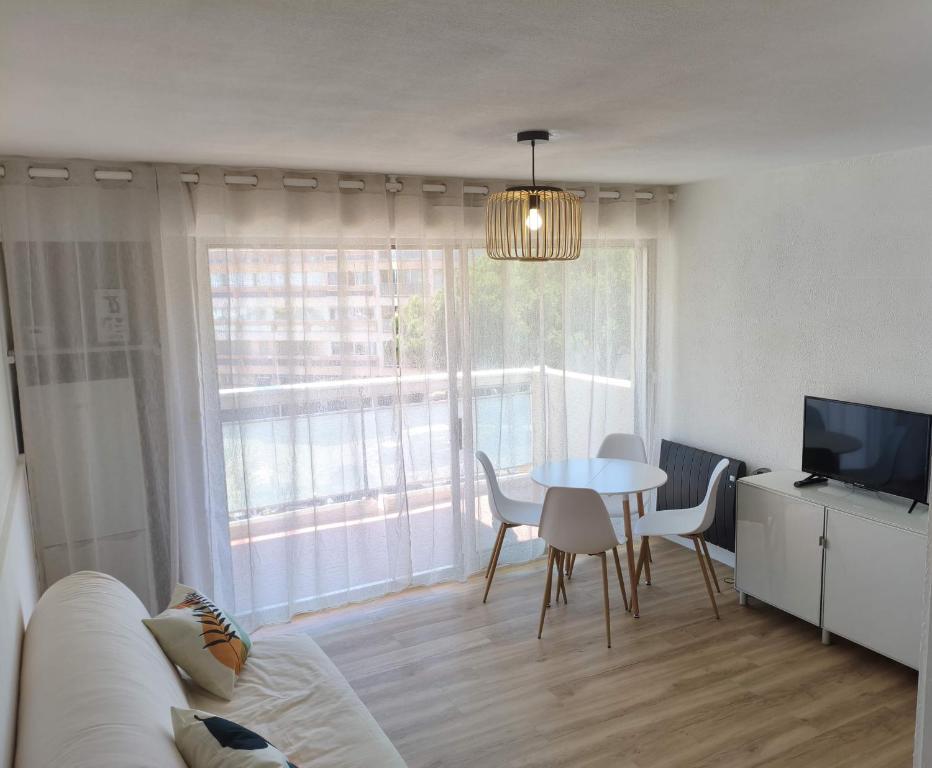 un salon avec un canapé et une table avec des chaises dans l'établissement Studio entre mer et port a Carnon plage, à Mauguio