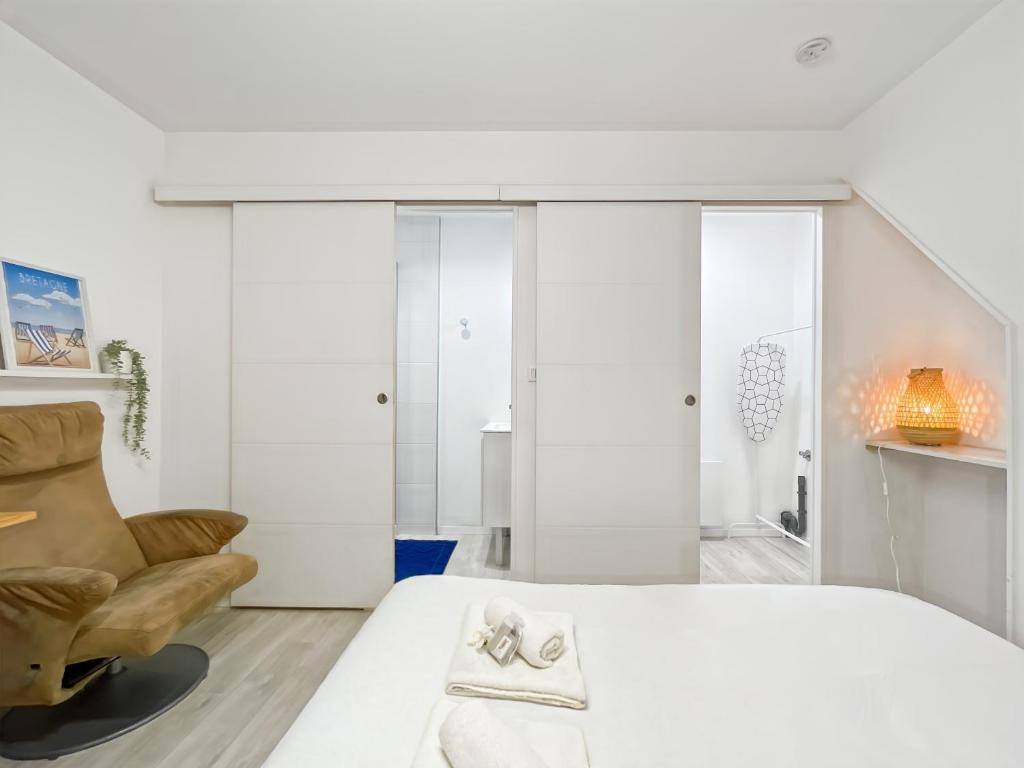 une chambre avec un lit blanc et une chaise dans l'établissement Lamirar - Centre Historique - Proche gare - Calme, à Rennes