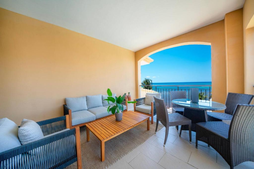 a balcony with a couch and chairs and a table at Condo Surf 405 - Luxury Oceanview Beachfront 3 BR with Gym - At El Faro Condos in Playa del Carmen