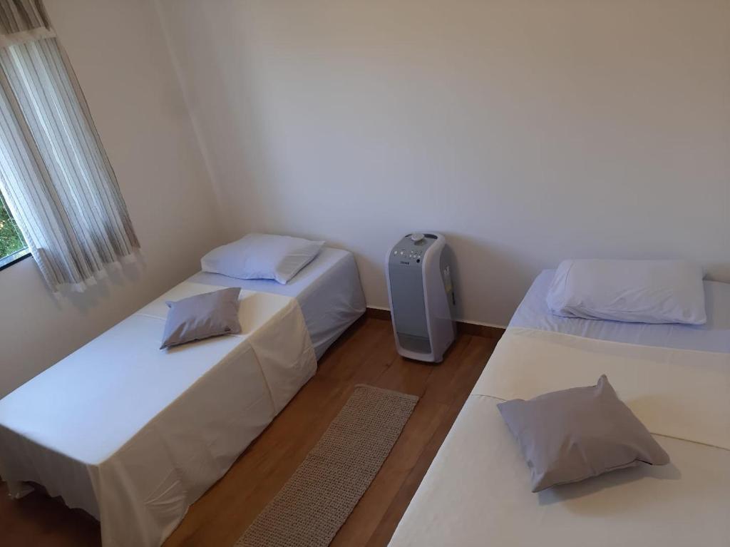 ein Zimmer mit zwei Betten und einem Fenster in der Unterkunft Privacidade para sua família e grupos em um só lugar-2 quartos- melhor custo-benefício, garagem, sala com cozinha integrada, aconchegante, ambiente moderno e funcional, wi-fi veloz gratuito, próximo ao Parque das Águas-Calçadão e tudo que a cidade oferece in São Lourenço