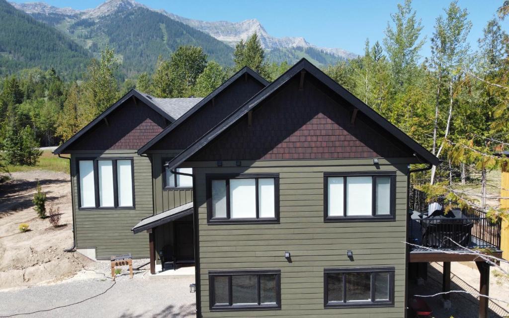 a house with mountains in the background at Powder House Chalet by Fernie Central Reservations in Fernie