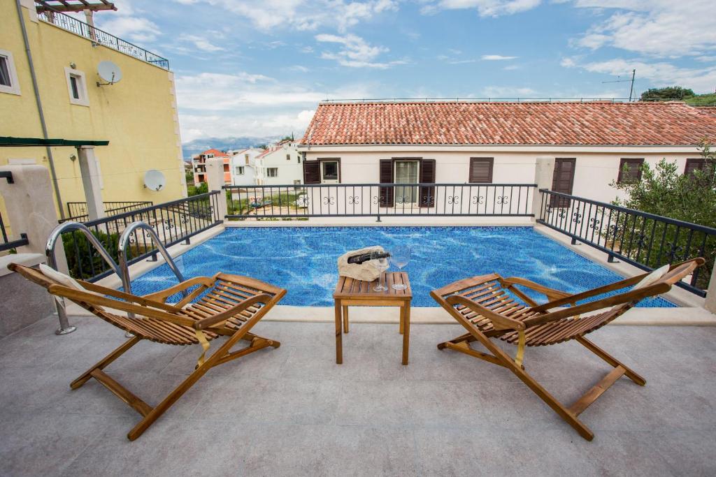a pool with two chairs and a table on a patio at Villa Suzy Lux in Sutivan