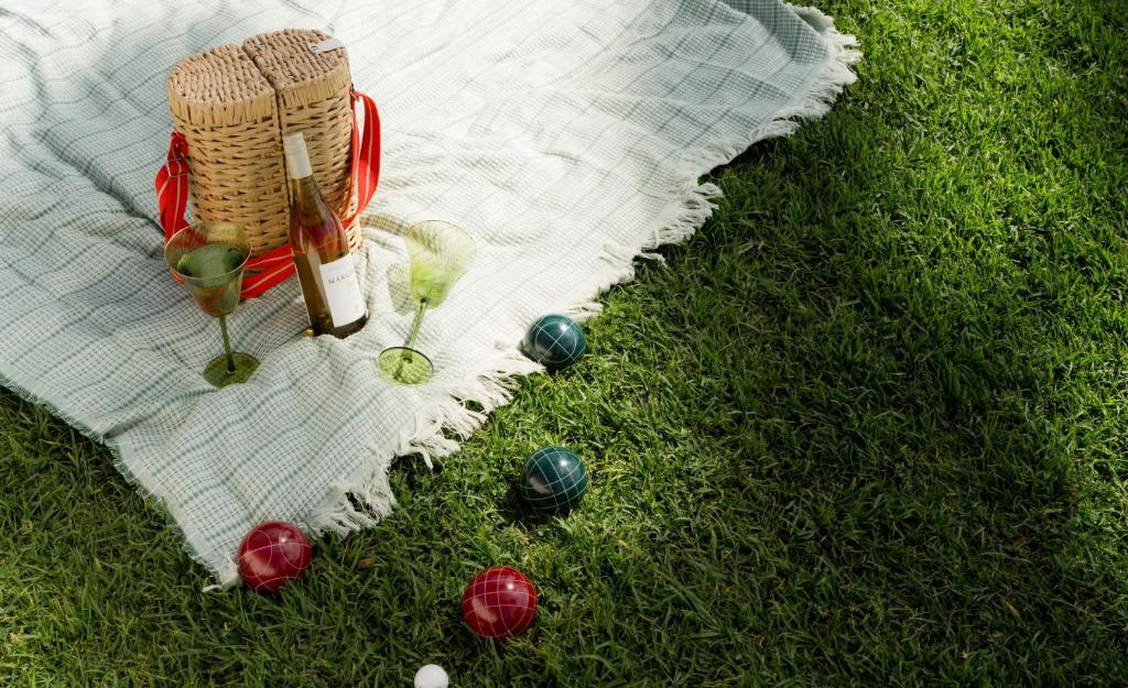 a picnic blanket with a bottle of wine and balls on the grass at The Milo in Santa Barbara