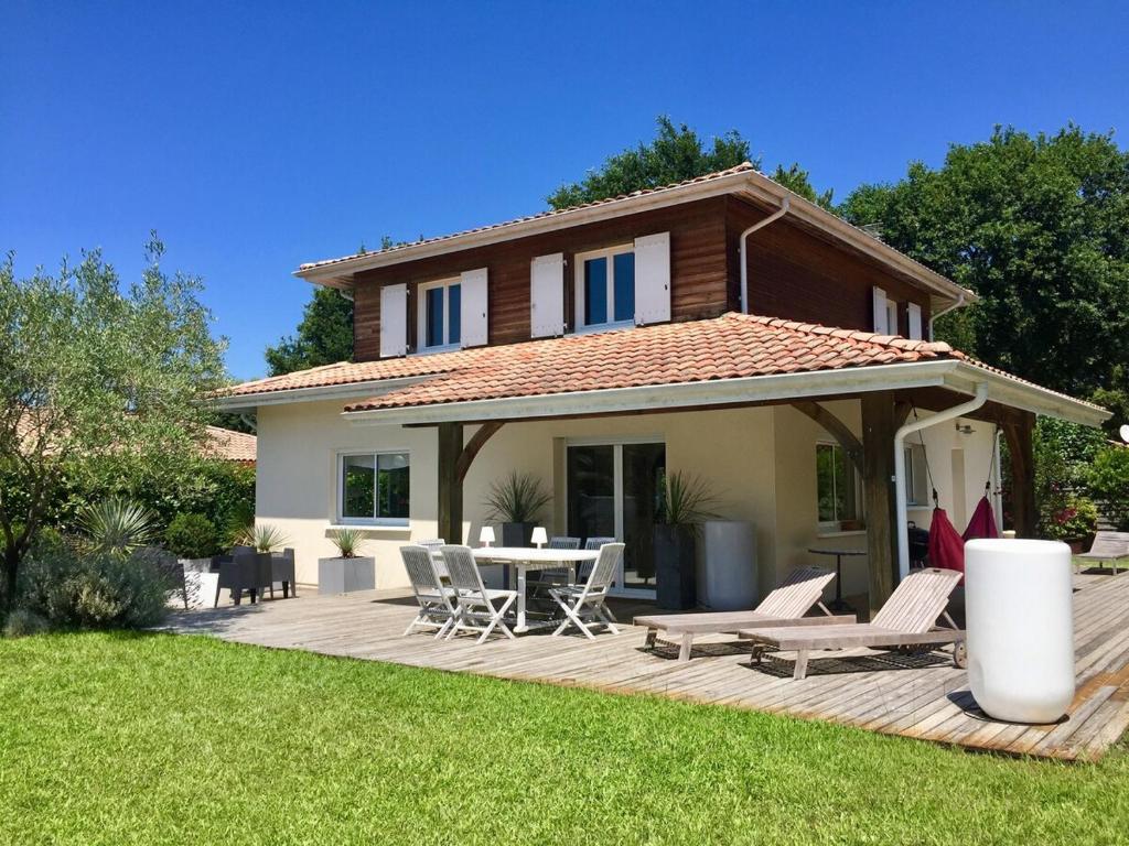 une maison avec une terrasse avec une table et des chaises dans l'établissement Maison calme 160m2 (1,8km plage), à Messanges