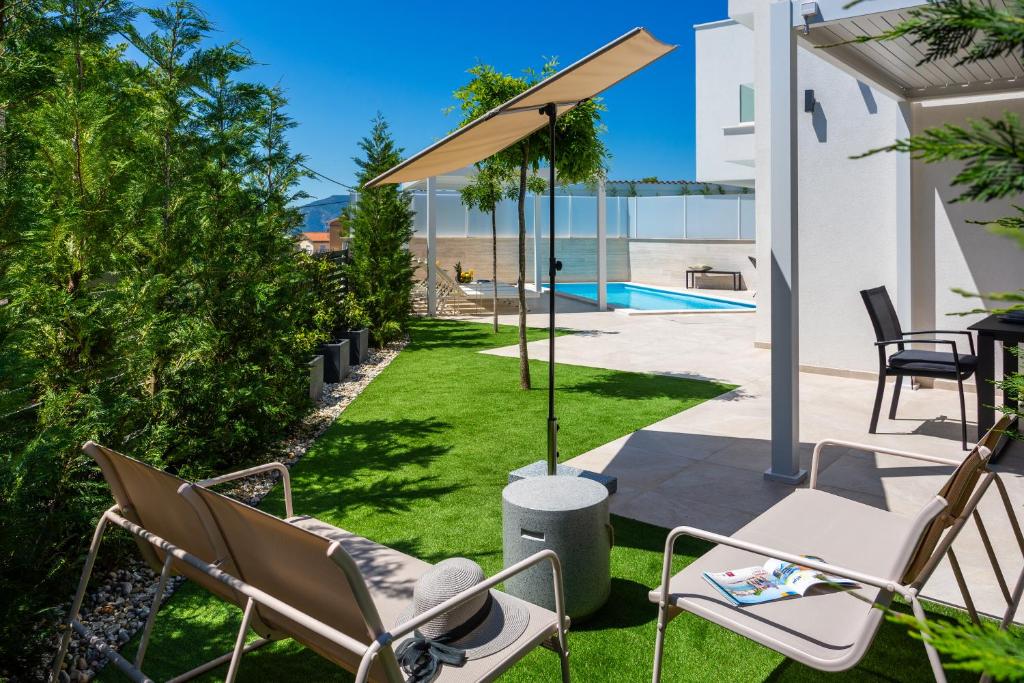 Un patio con sillas de jardín y una sombrilla. en Villa Arta, en Linardići