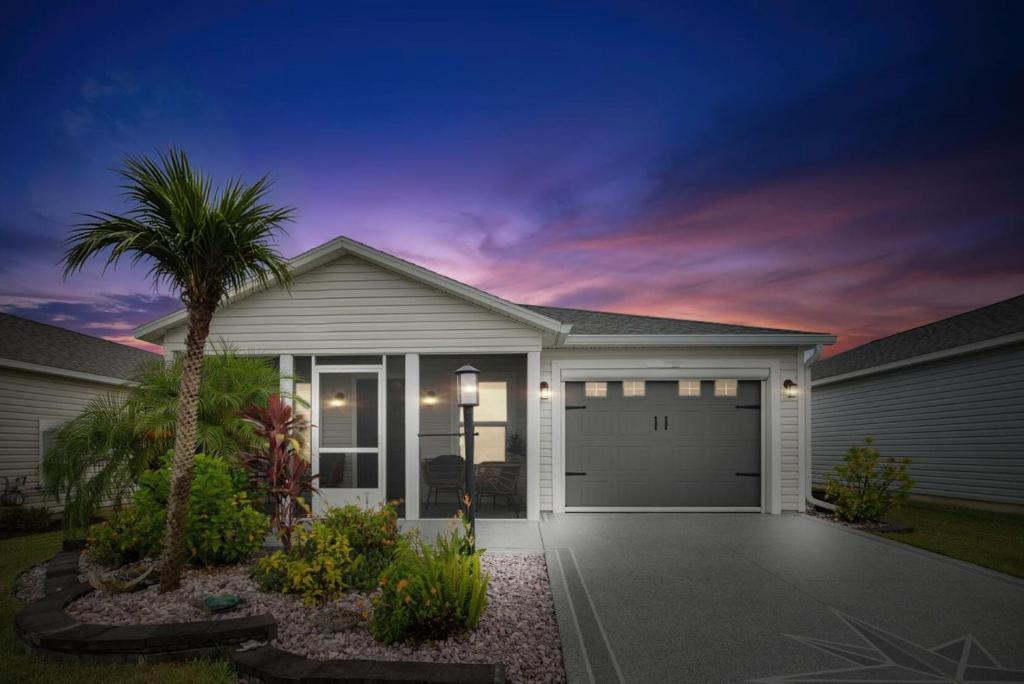 a house with a garage and a palm tree at King Sized Comfort in The Village of Deluna in The Villages