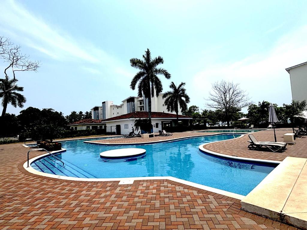 a large swimming pool with palm trees and a building at Spacious Beachfront Condo 3202 | Playa Bejuco + Pool + Direct Beach Access in Bejuco