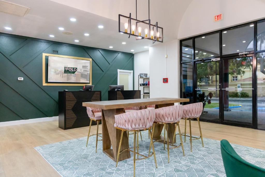 a dining room with a table and pink stools at The Fold Hotels Orlando in Orlando
