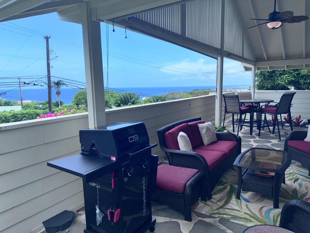 a screened in porch with chairs and a table and a tv at Pines182 in Kailua-Kona