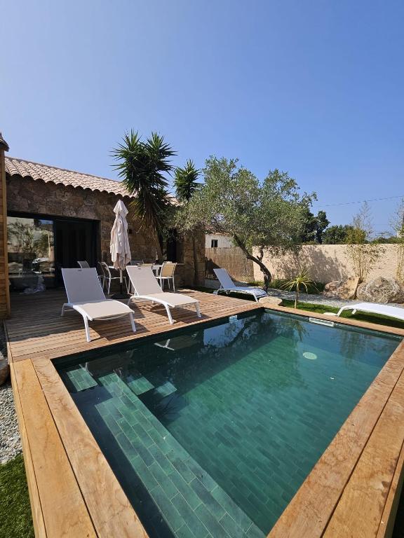 une piscine avec des chaises et une maison dans l'établissement Maison Di Fiori, location neuve avec piscine, à Porto-Vecchio