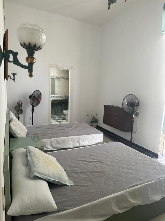 two beds in a room with two lamps and a television at مجمع ديار بالساحل الشمالي in Sidi Kirayr