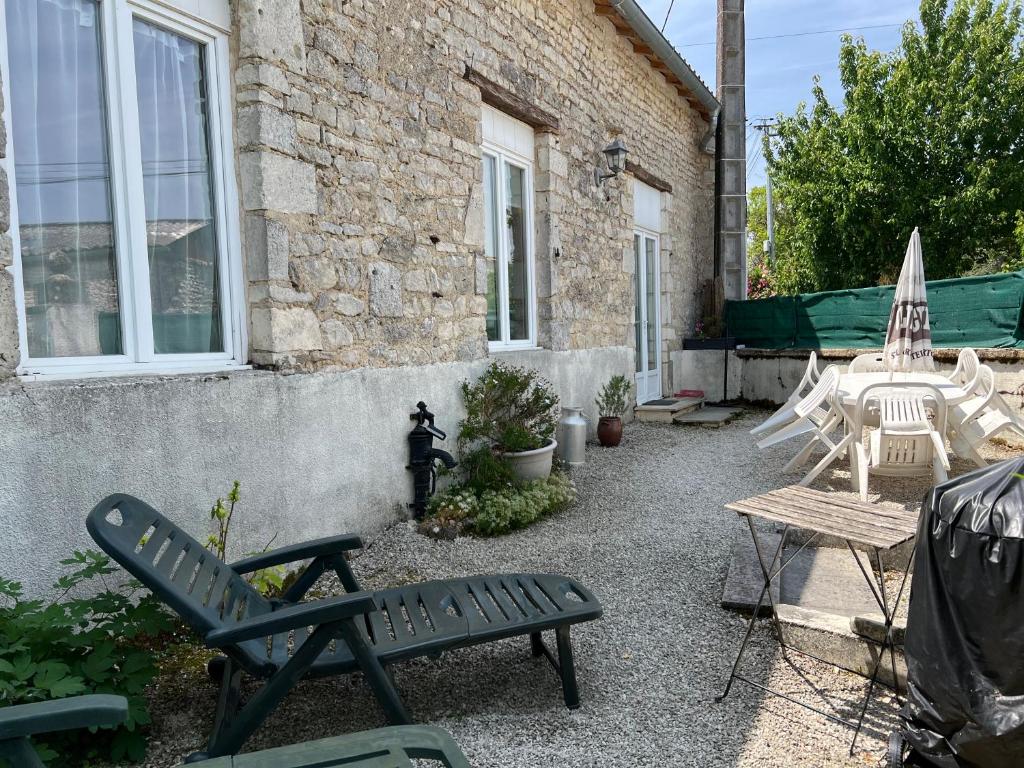 a patio with chairs and a table and an umbrella at Gîte de l'hortensia-Charmante maison de campagne au calme in Gourville