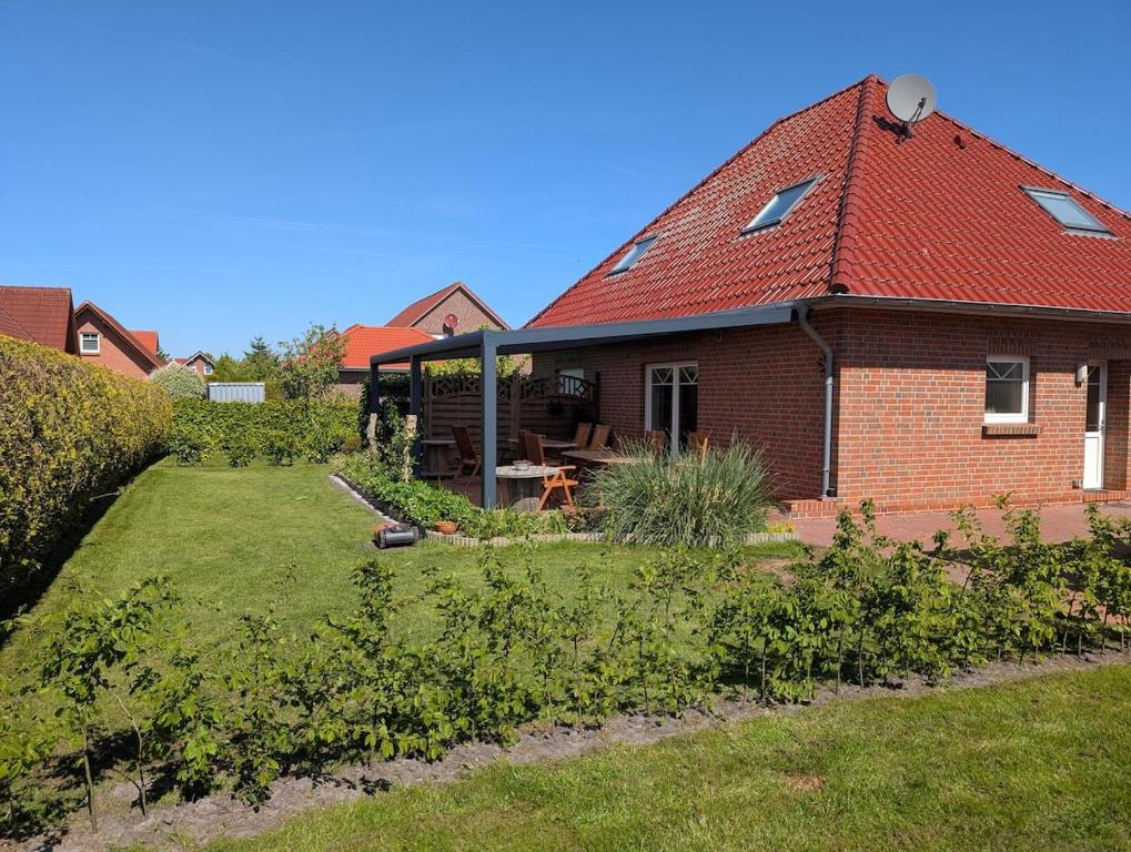 a brick house with a red roof and a yard at Ferienhaus Lina in Südbrookmerland