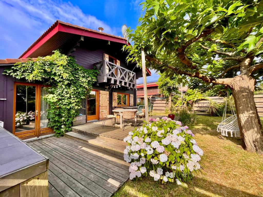 una terrazza in legno di fronte a una casa con fiori di Maison en bois en 2ème ligne a Gujan-Mestras