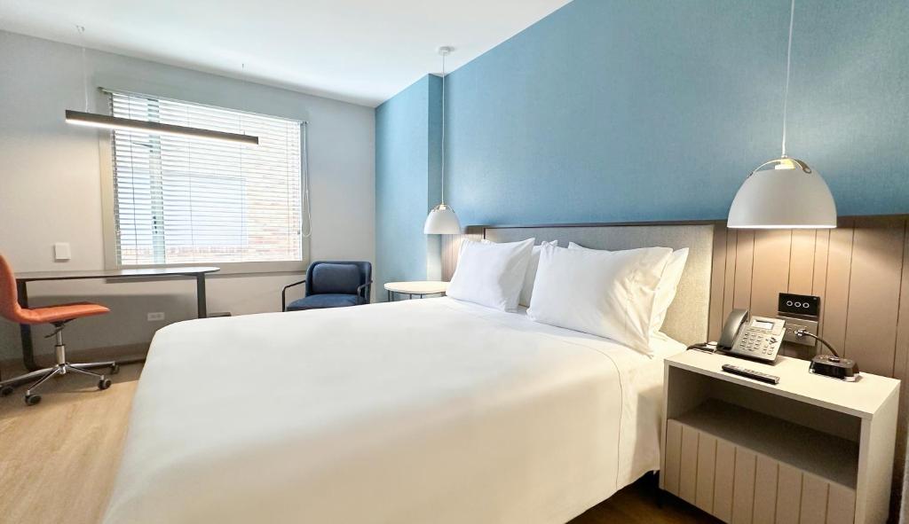 a hotel room with a large white bed and a phone at Hotel Habitel Select in Bogotá