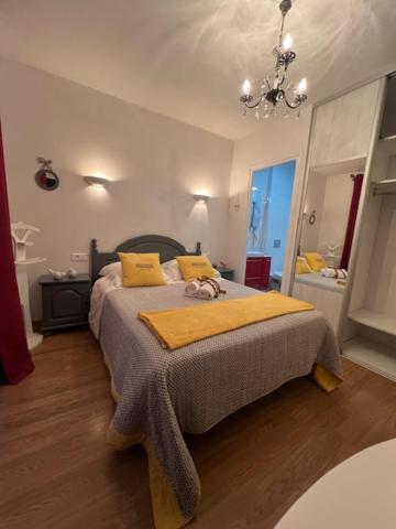 ein Schlafzimmer mit einem Bett mit gelben Kissen und einem Kronleuchter in der Unterkunft Chambres d'hôtes La Rose Des Sables in Les Herbiers