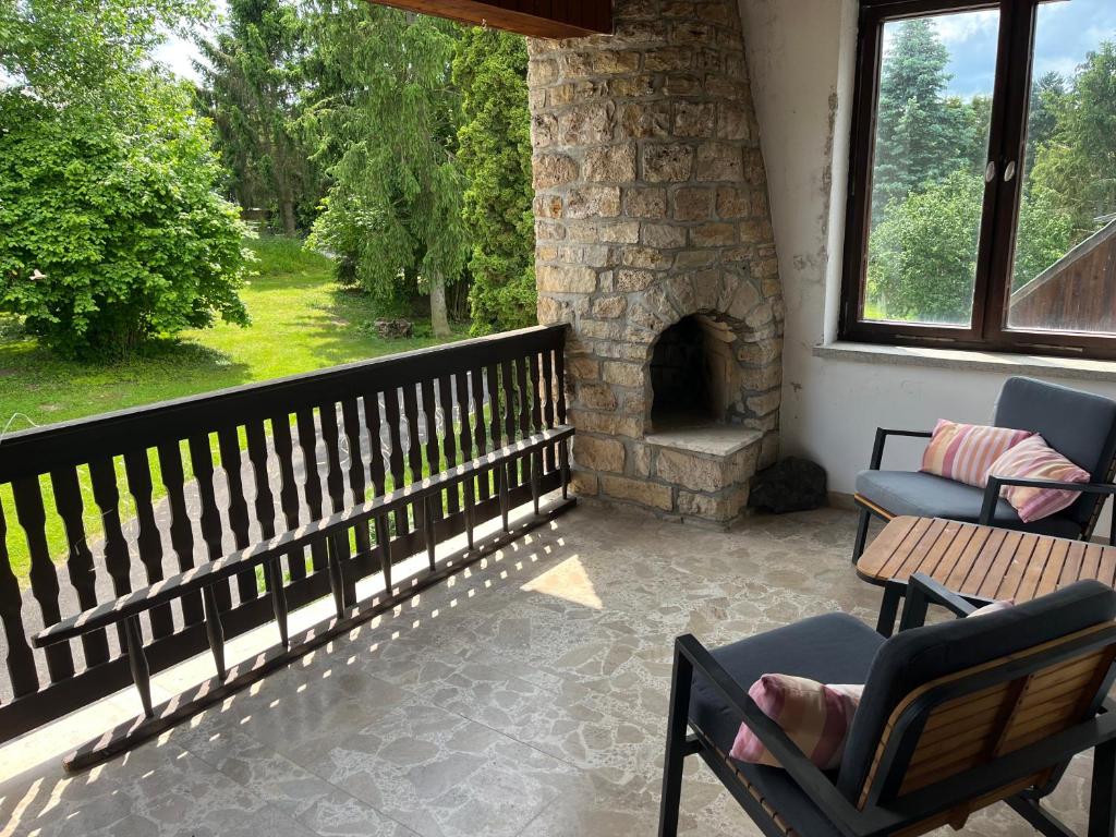 a porch with two chairs and a stone fireplace at Ferienhaus im Grünen in Weimar