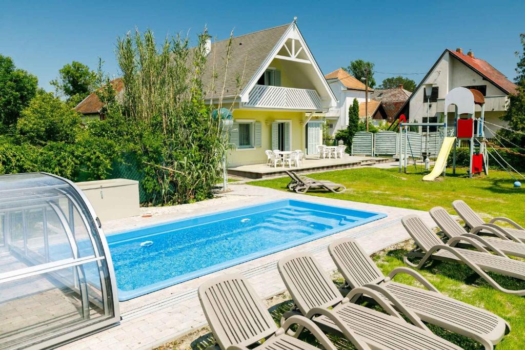 a backyard with a pool and chairs and a house at Holiday home in Balatonmariafürdo 38170 in Balatonmáriafürdő