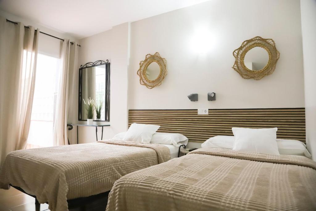 a bedroom with two beds and mirrors on the wall at Hostal Cuevas in Fuengirola