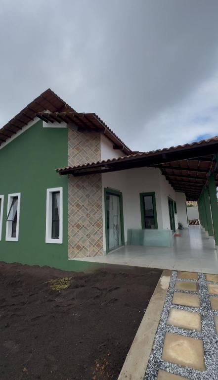 a green and white house with a driveway at Suítes Refúgio Serrano in Bananeiras
