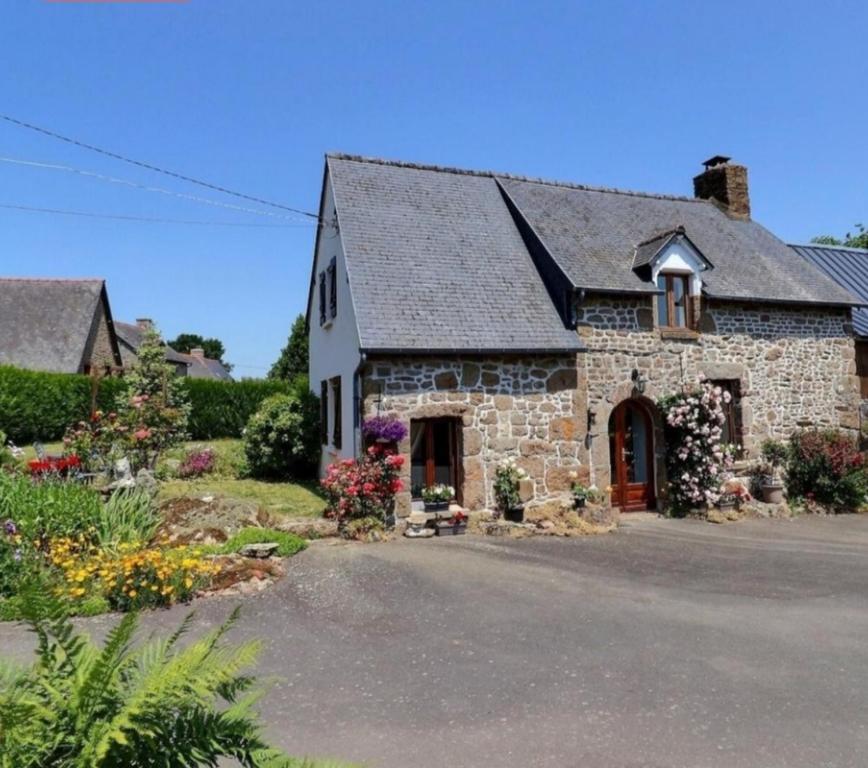 an old stone house with flowers in front of it at Kanevedenn in Val Couesnon