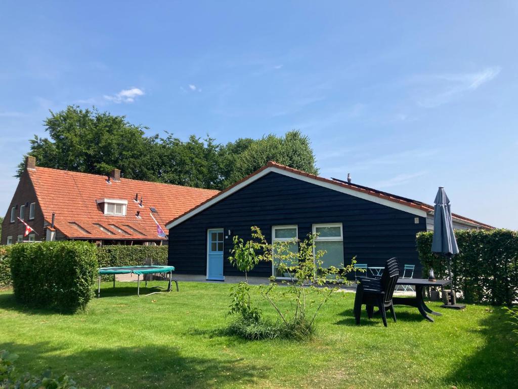 una casa negra con una mesa de picnic en el patio en Bungalow Buitenlui, en Molenschot